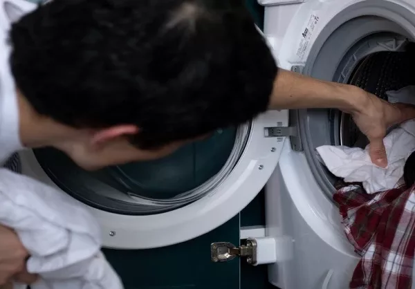 A man pulling out clothes from a washing machine