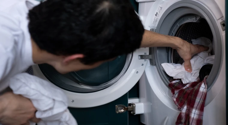 A man pulling out clothes from a washing machine
