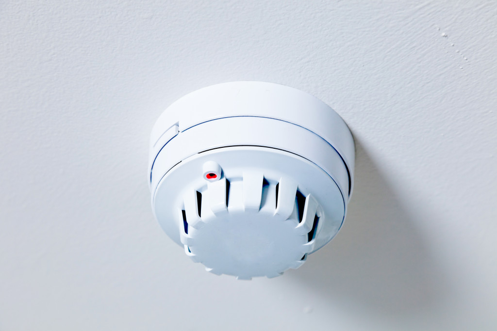 A white smoke detector with an alarm system attached to a ceiling