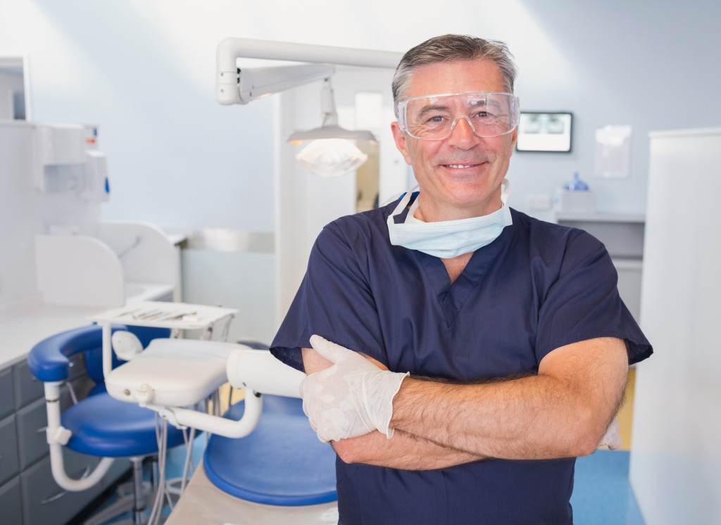 Portrait of a smiling dentist with arms crossed in dental clinic