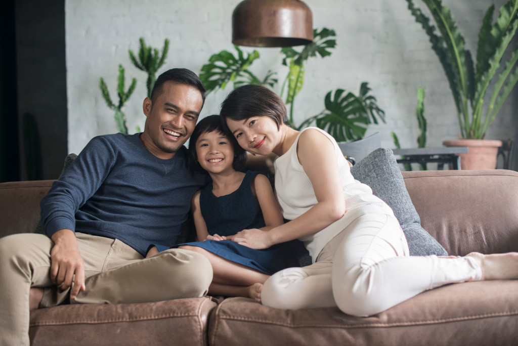 father, mother, and daughter sitting on a couch, happy and smiling