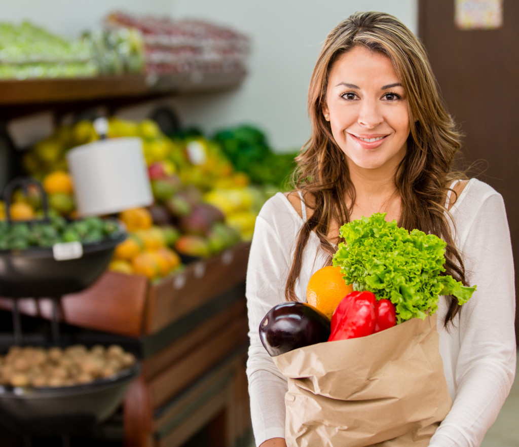 A woman in holding a bag of fresh produce bought from a local market