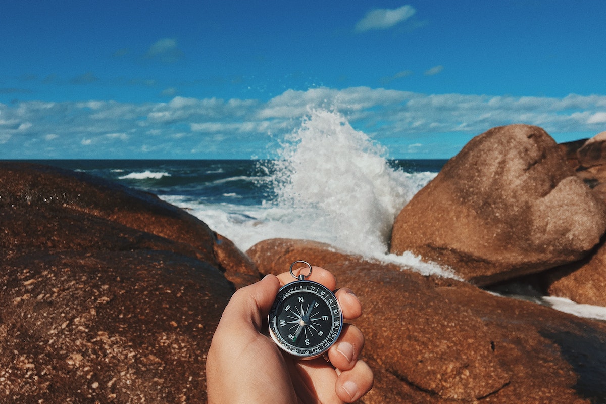 Crop traveler with compass on stony seashore