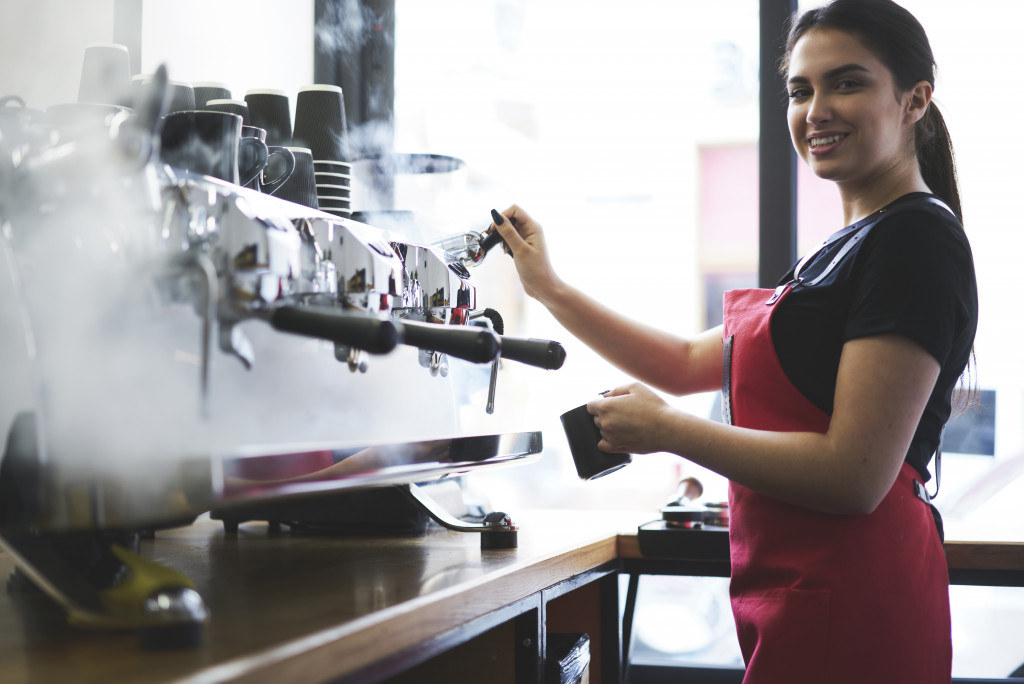 A female bartender using an espresso machine making coffee