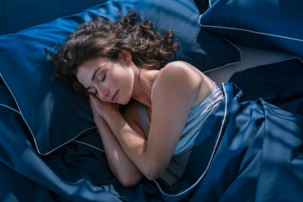 Young woman sleeping soundly in a bed with blue covers.