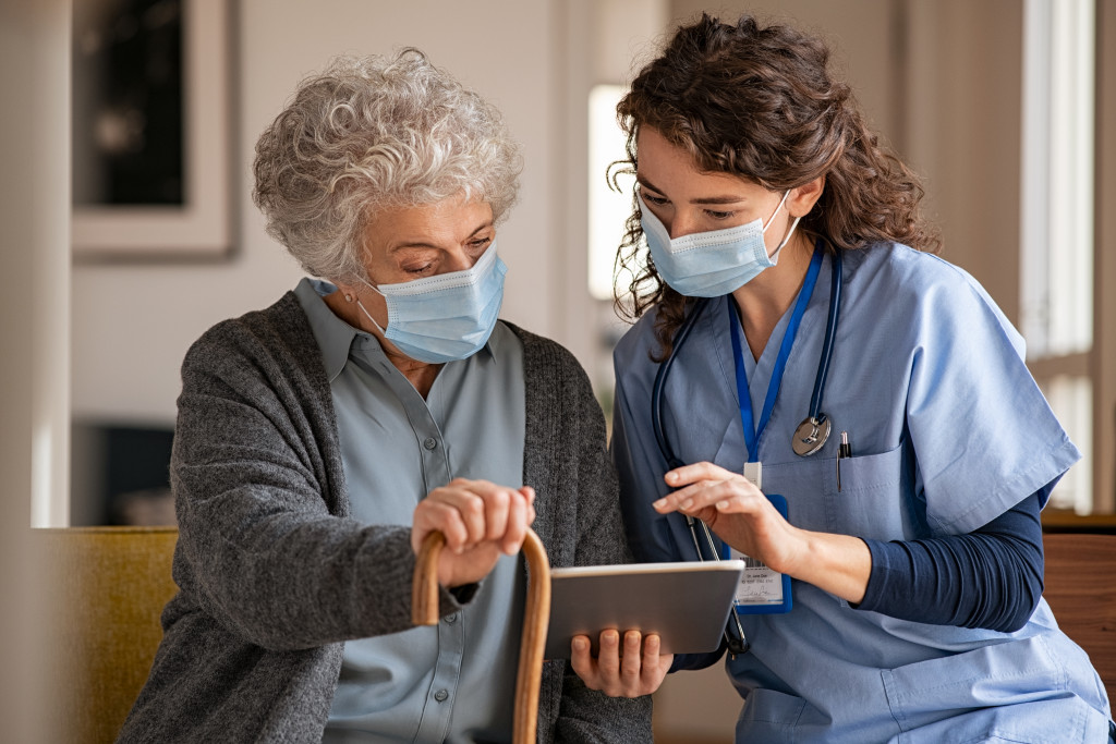 female nurse teaching an elderly woman how to use her tablet