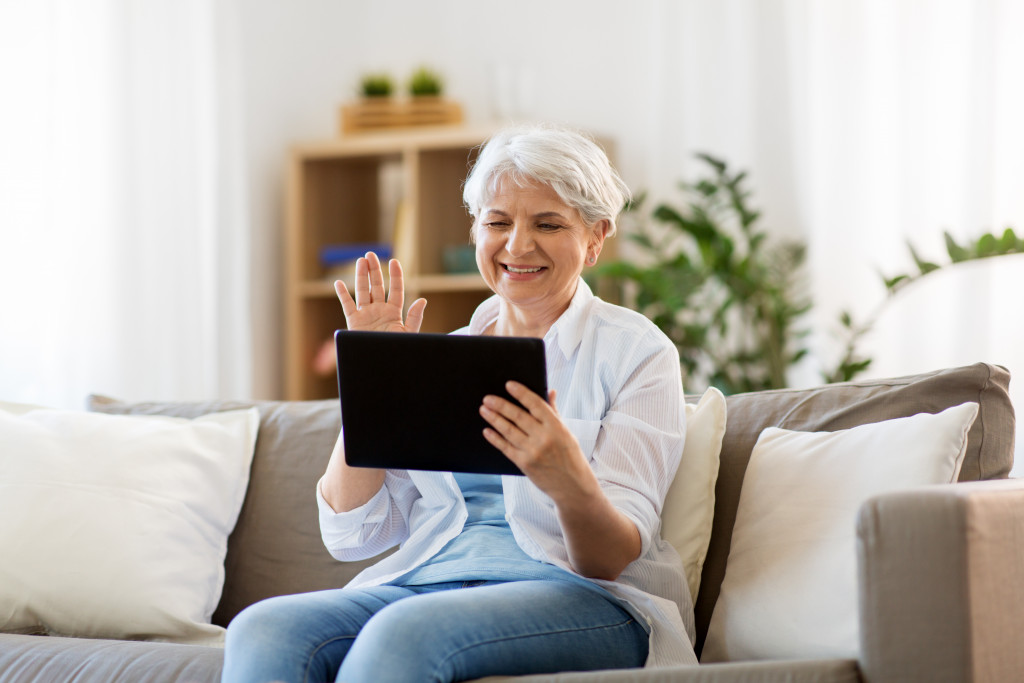 elderly woman using tablet to have a video call with other people at home