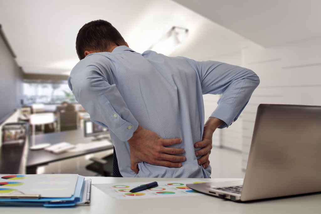 male business owner holding back as it aches in his office