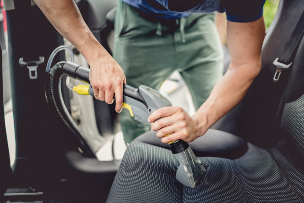 man vacumming the interior of his car