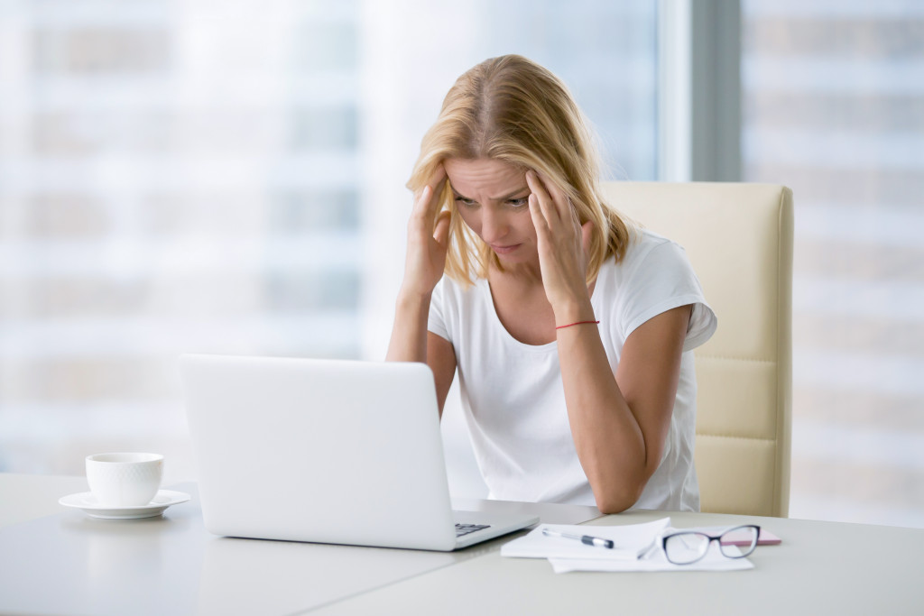 stressed female entrepreneur looking at laptop with hand in her head