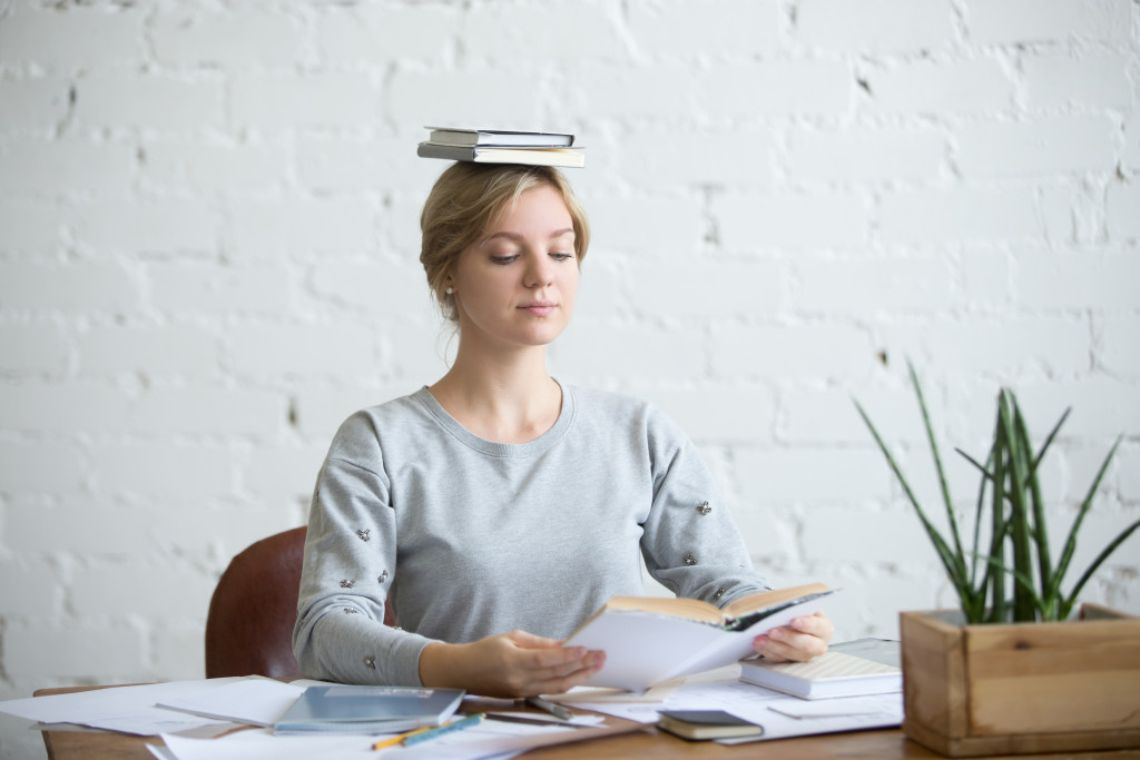 A woman with a book on her head practicing good posture while sitting